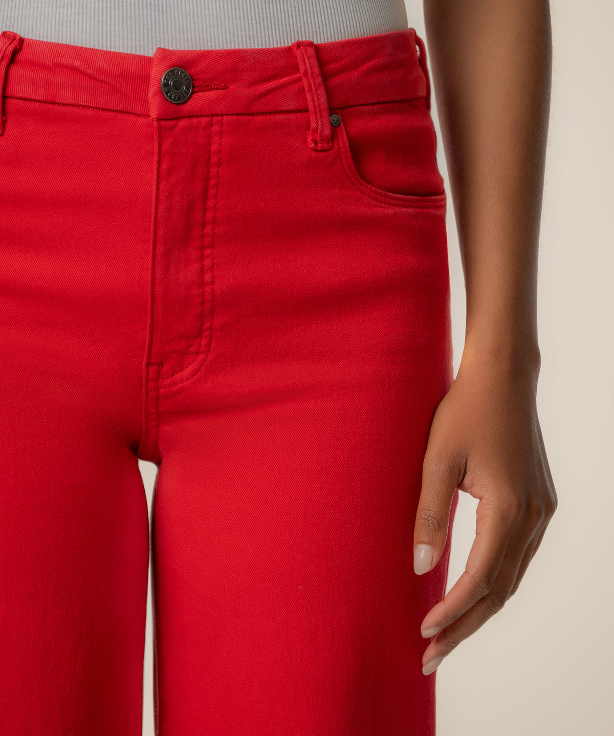 Red high-rise wide-leg pants with button closure and visible seams, worn at waist level.