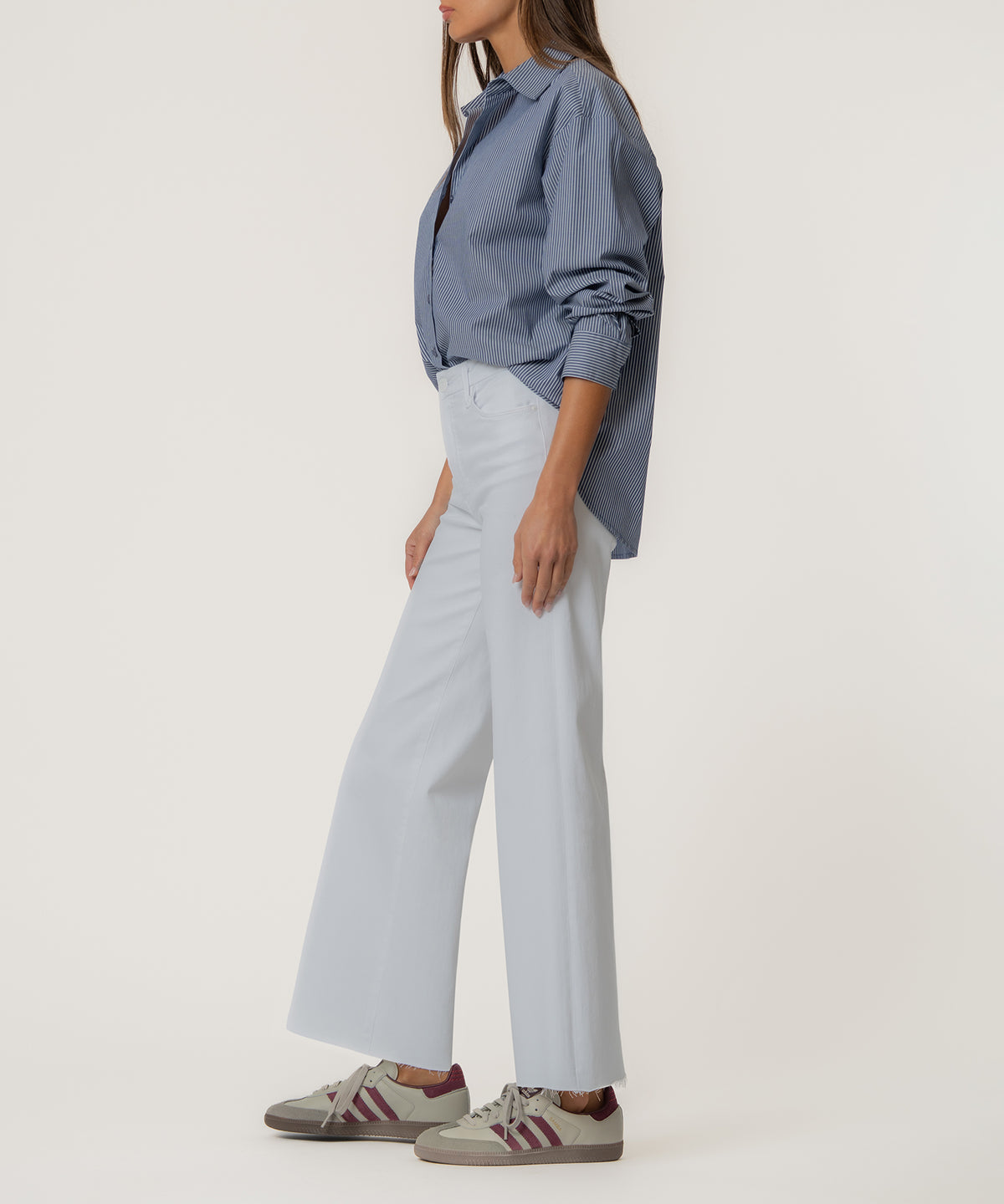 Woman wearing optic white high-rise wide-leg jeans with long inseam paired with blue striped shirt.