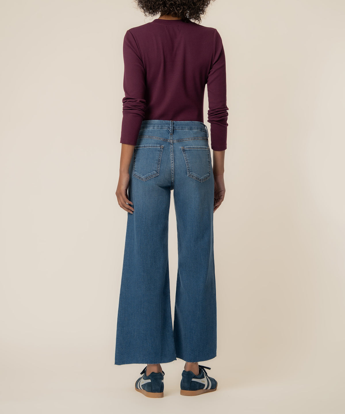 Woman wearing high-rise wide-leg jeans in medium blue denim with cropped length, shown from behind.