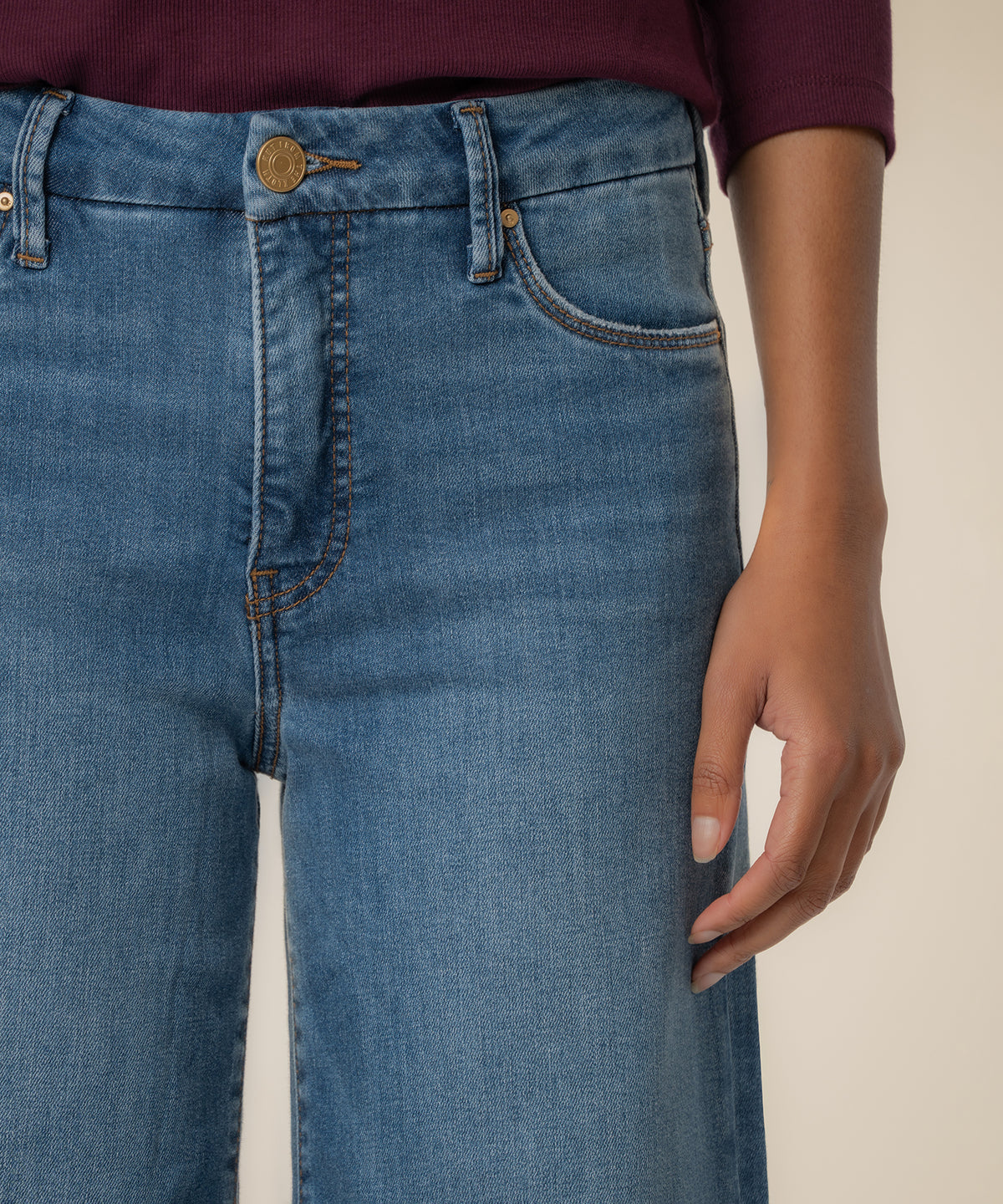 High-rise wide-leg jeans in light blue wash with gold button and five-pocket styling.