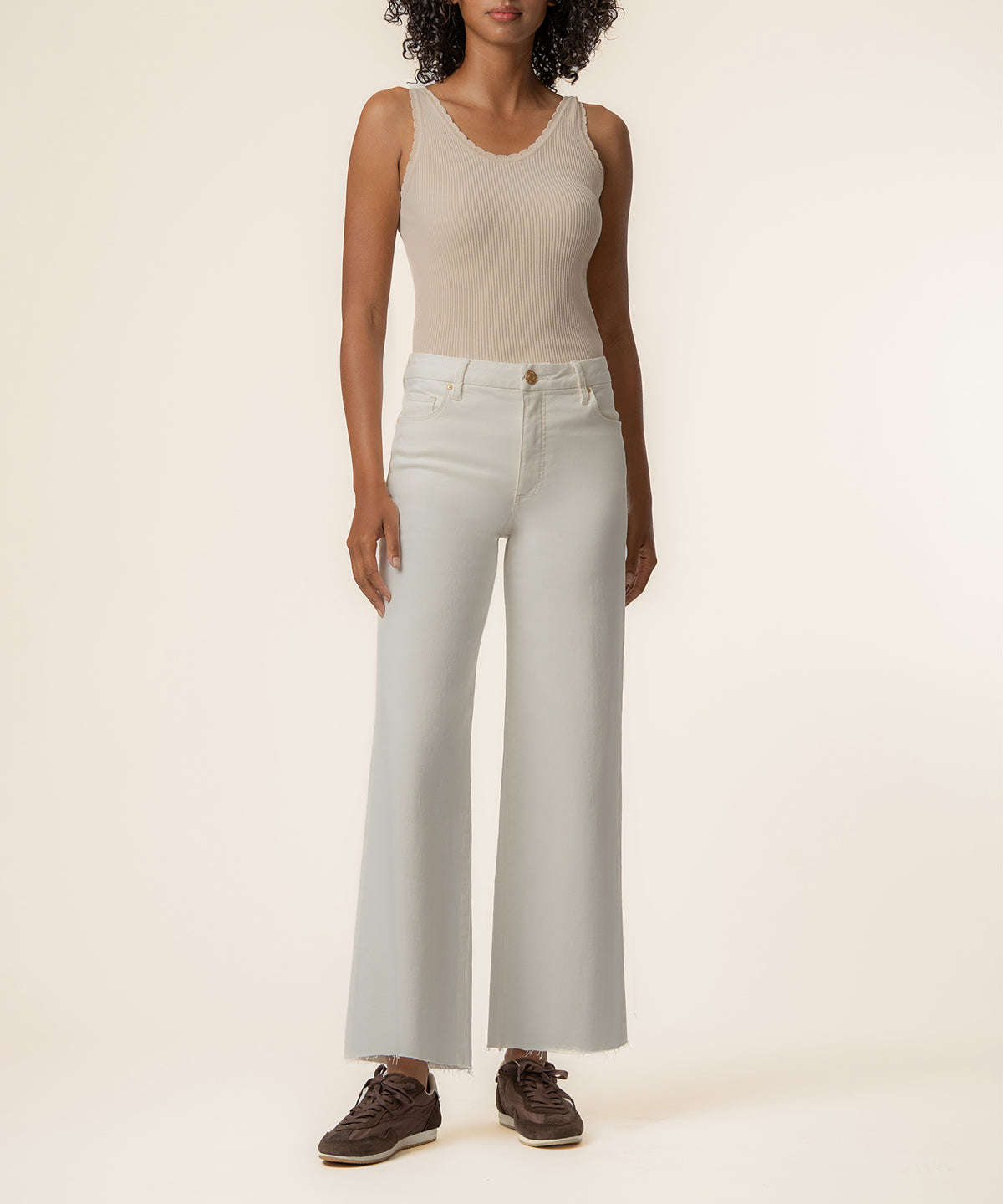 Ecru high-rise wide-leg jeans worn with a ribbed cream tank top and brown lace-up boots.