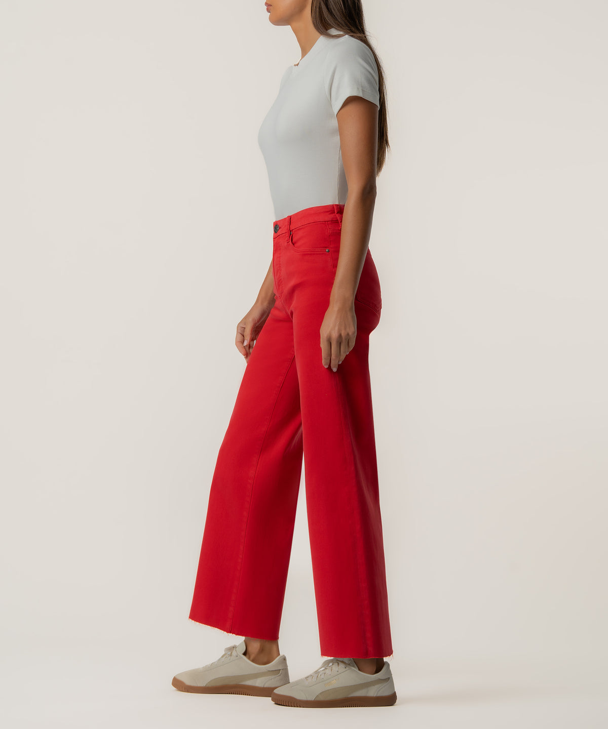 Woman wearing light gray t-shirt and scarlet red high-rise wide-leg jeans with cream sneakers.