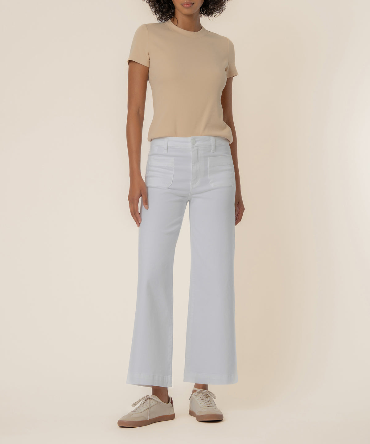 Woman wearing optic white high-rise wide-leg jeans with a beige t-shirt and tan shoes.