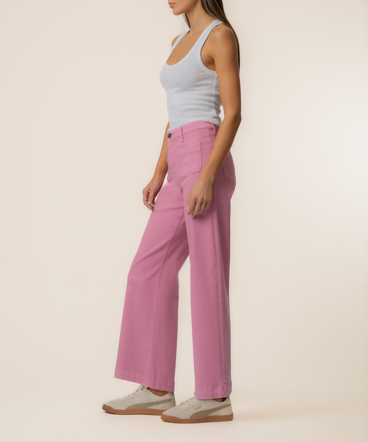 Woman wearing pink high-rise wide-leg jeans with a white tank top and white sneakers.
