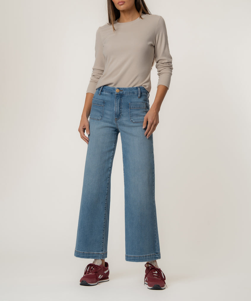 Woman wearing beige long-sleeve top and light-wash high-rise wide-leg jeans with burgundy sneakers.