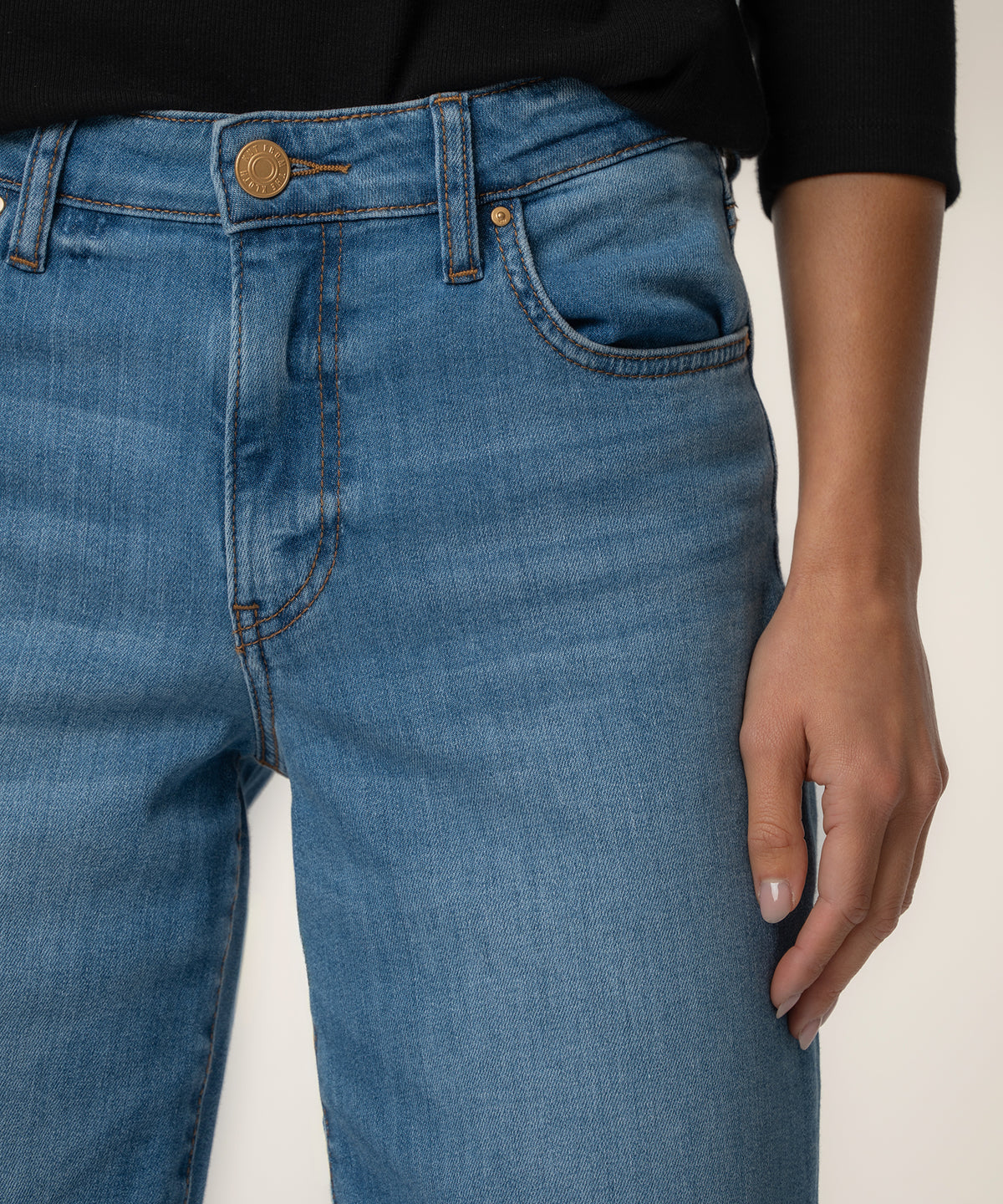 High-rise wide-leg jeans in light blue denim with gold button and brown stitching detail.