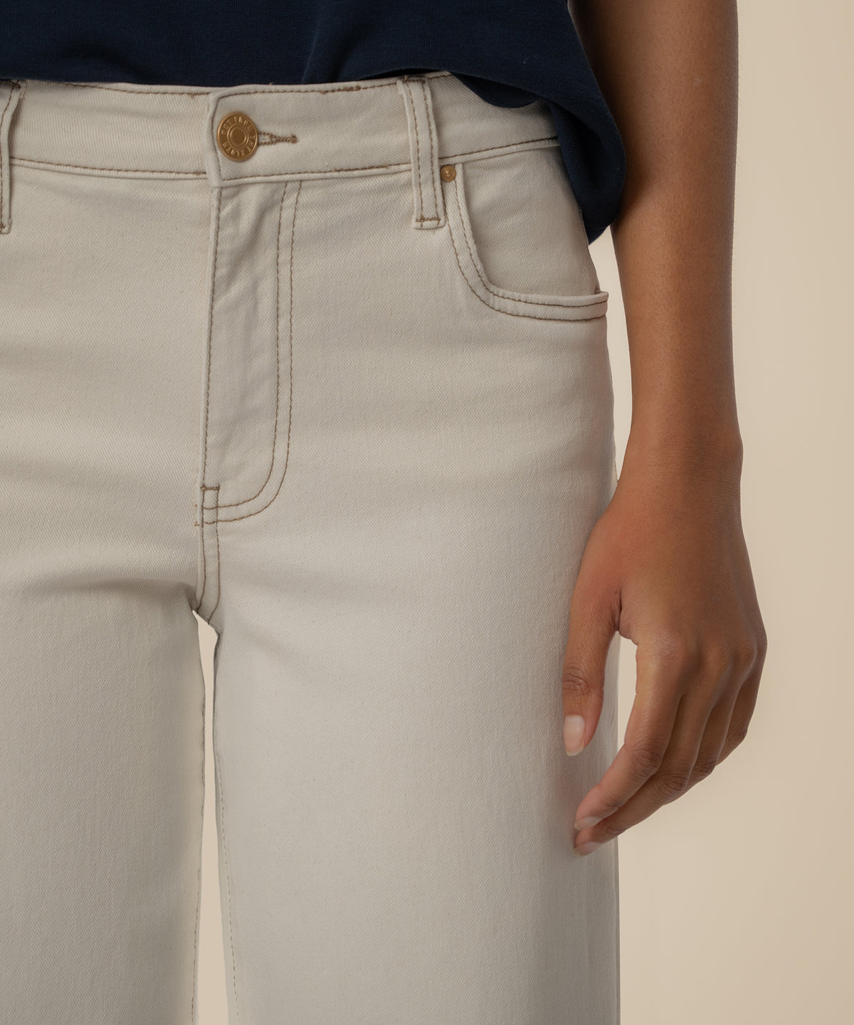 Ecru high-rise wide-leg jeans with gold button and visible stitching detail at waistband.
