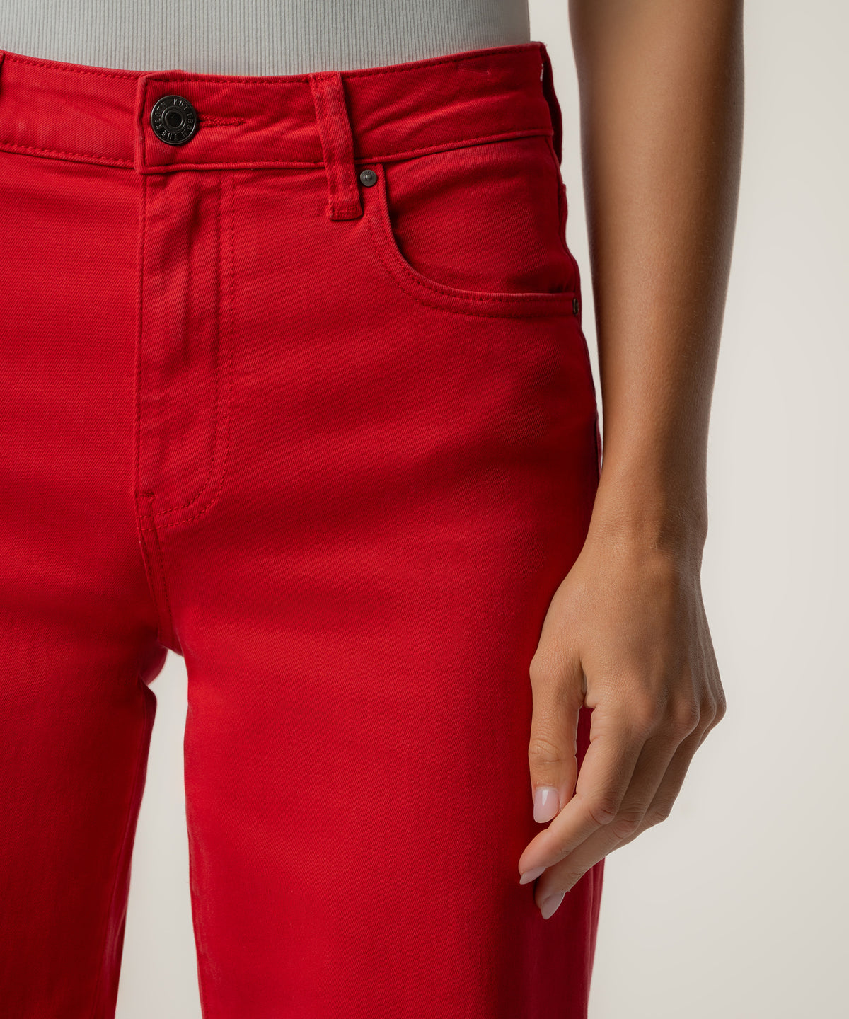 Scarlet red high-rise wide-leg pants with button fly and front pockets, shown at waistband detail.