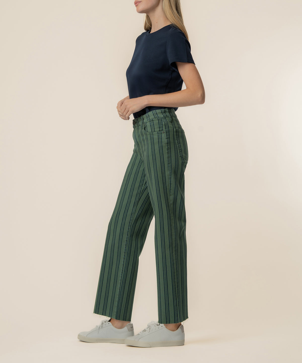 Woman wearing matcha green high-rise wide leg pants with vertical stripe pattern and navy short-sleeve shirt.