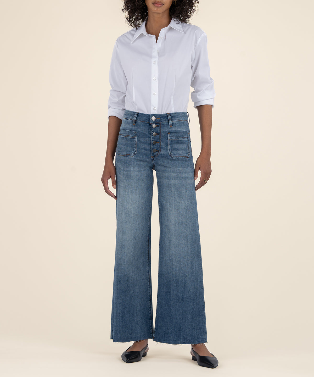 Woman wearing light blue button-up shirt and high-rise wide-leg medium wash denim jeans with button fly.
