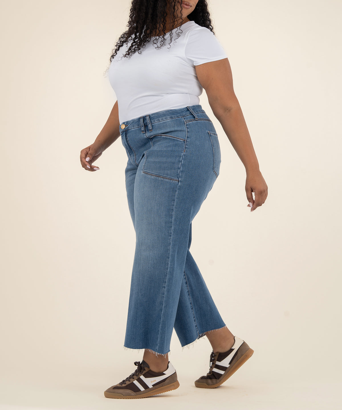 Woman wearing high-rise wide-leg jeans in medium blue denim with white t-shirt.