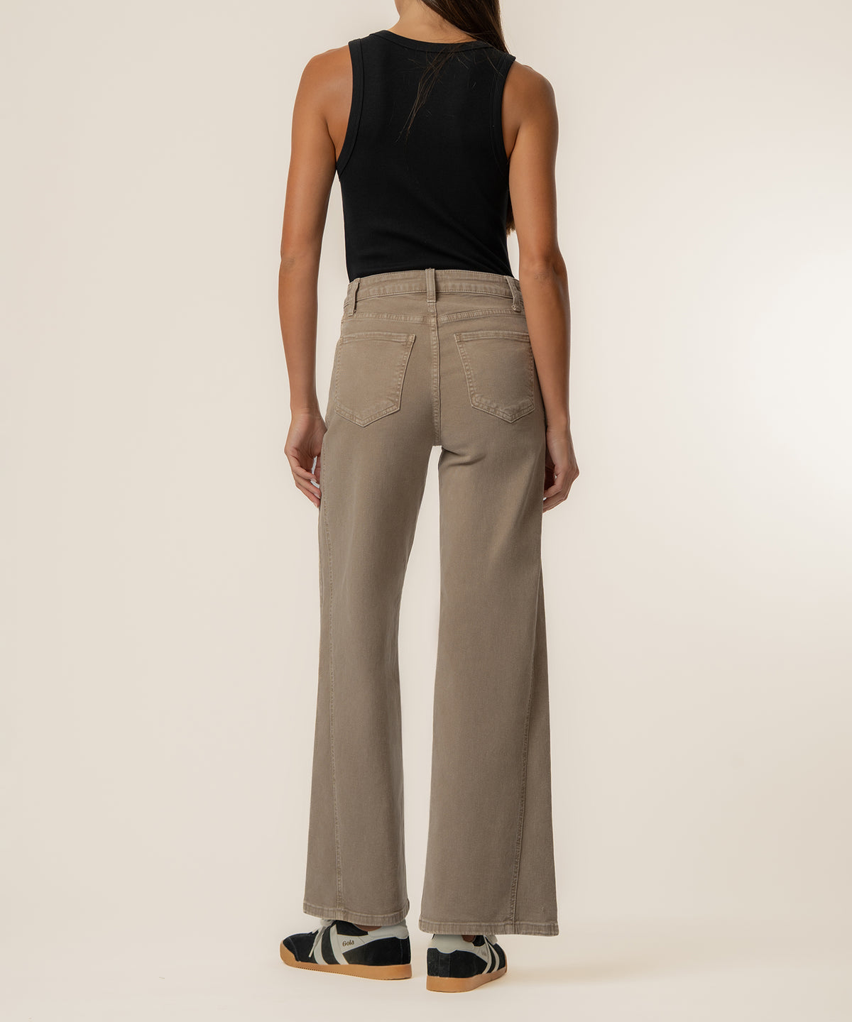 Woman wearing beige wide-leg jeans with high rise waistband and black sleeveless top, back view.