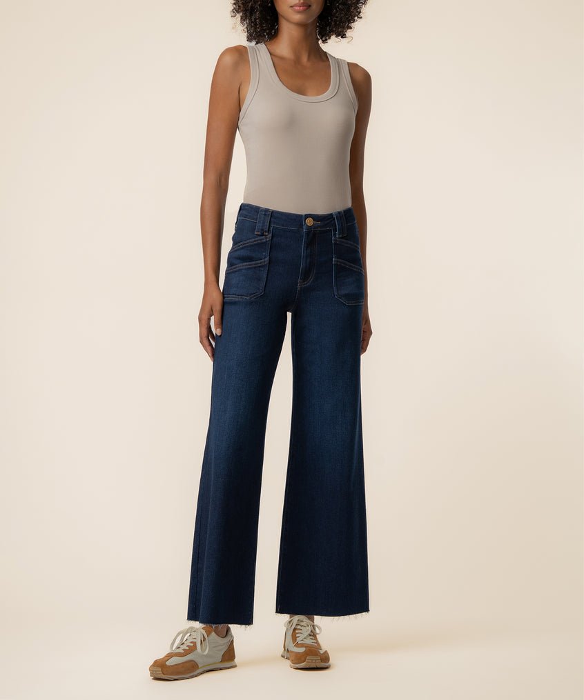 Dark blue wide-leg jeans with high rise waist and patch pockets worn with a beige sleeveless tank top.
