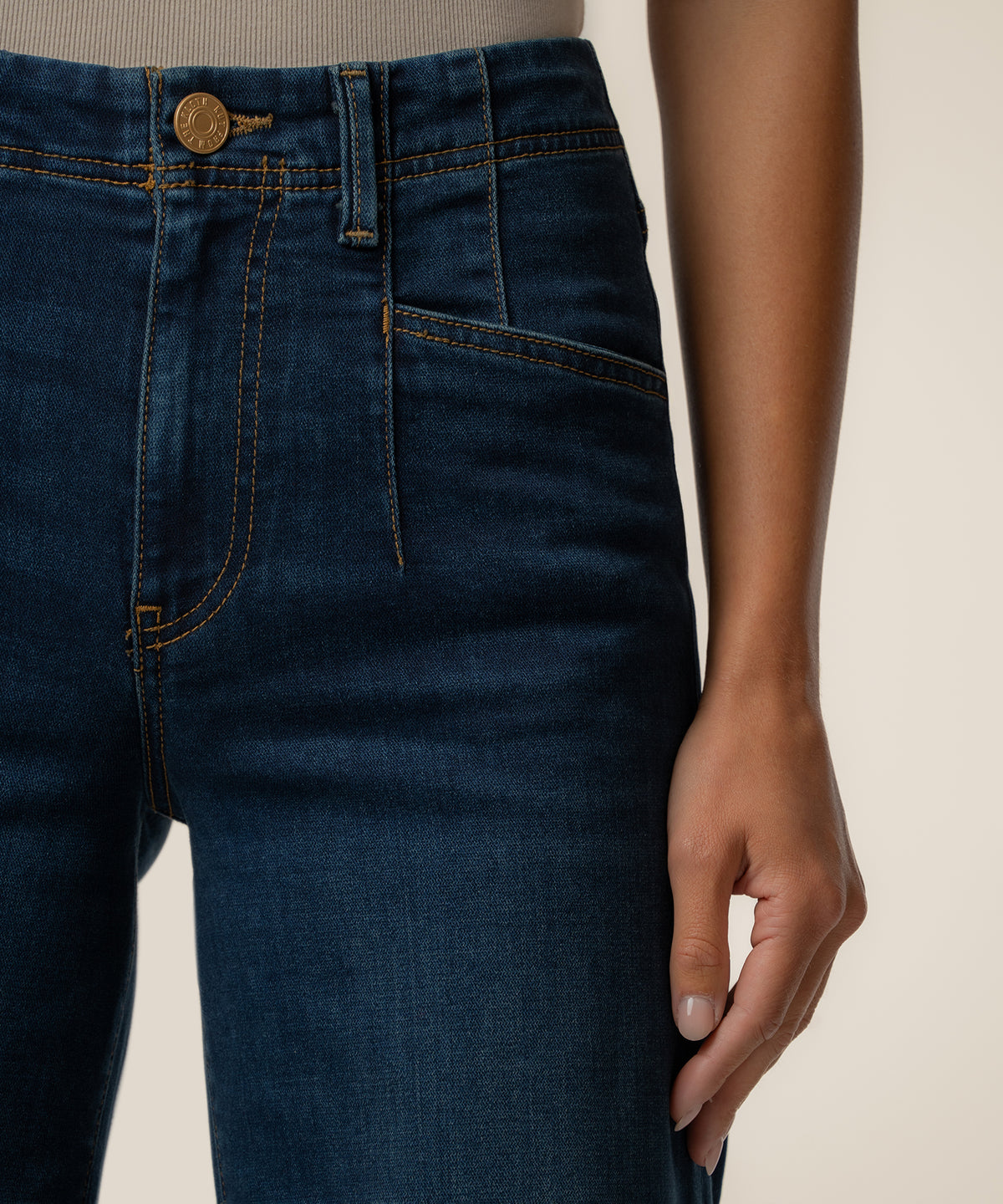 Dark indigo high-rise wide-leg jeans with orange topstitching and gold button closure.