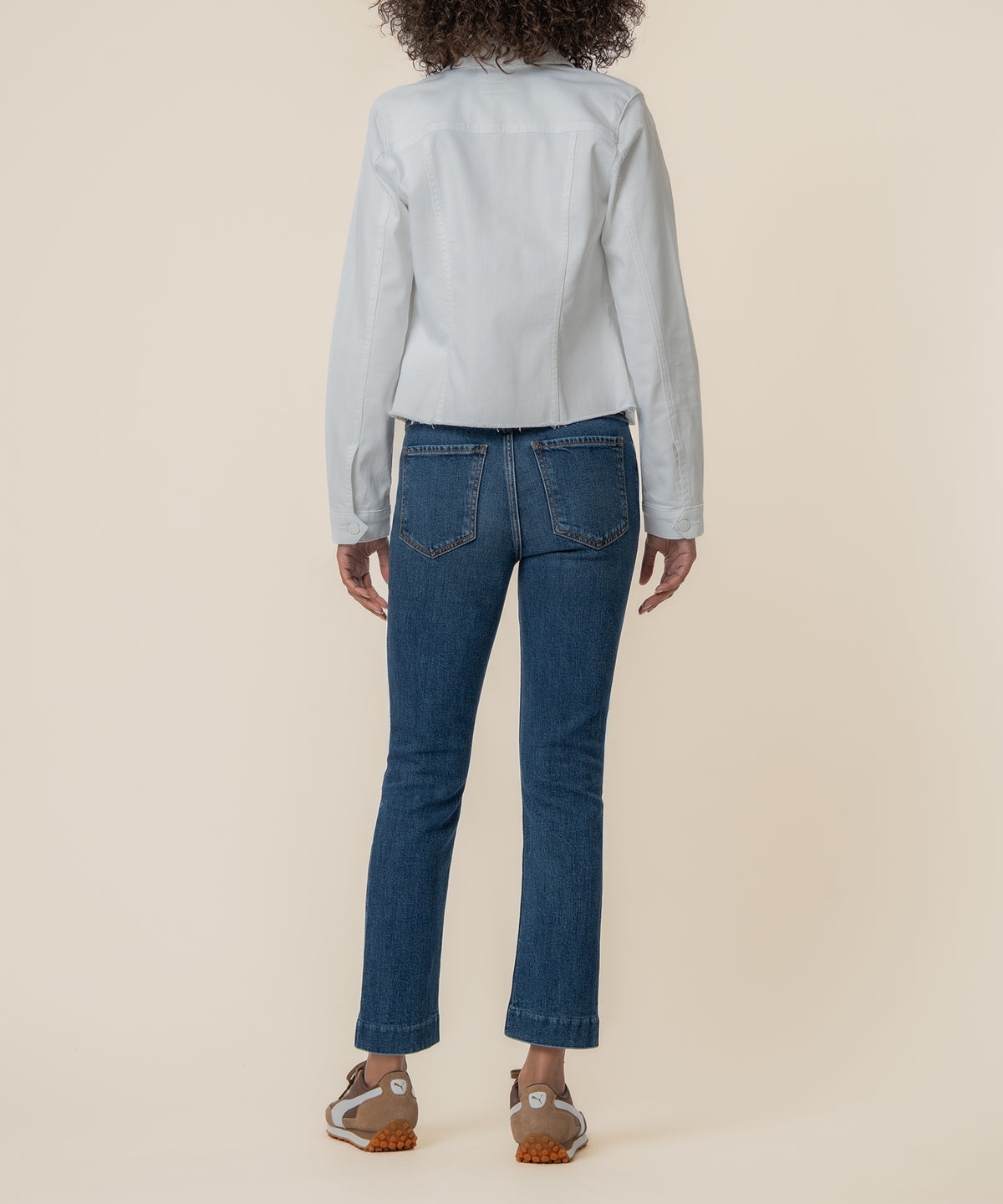 White denim jacket with long sleeves shown from back view on model wearing blue jeans.