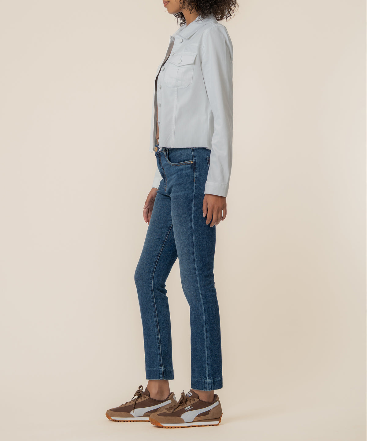 White denim jacket with button front and chest pocket, styled with blue jeans and brown sneakers.