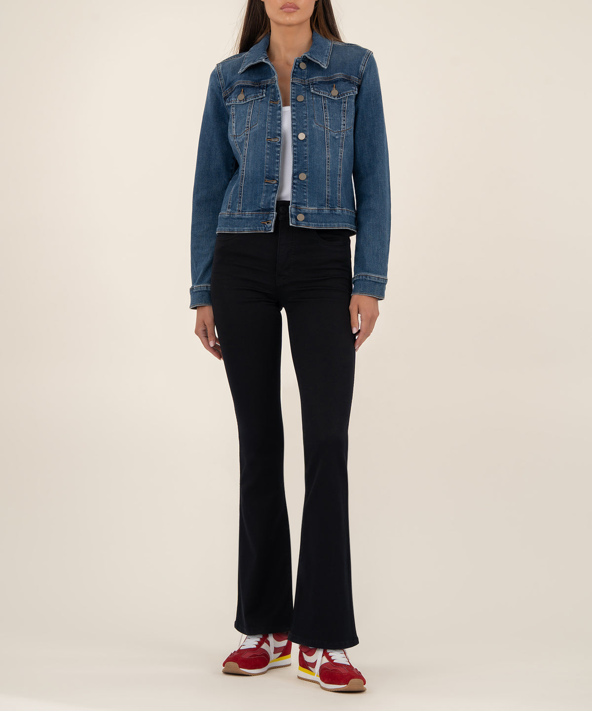 Woman wearing a cropped blue denim jacket with button front and chest pockets over black flared pants.