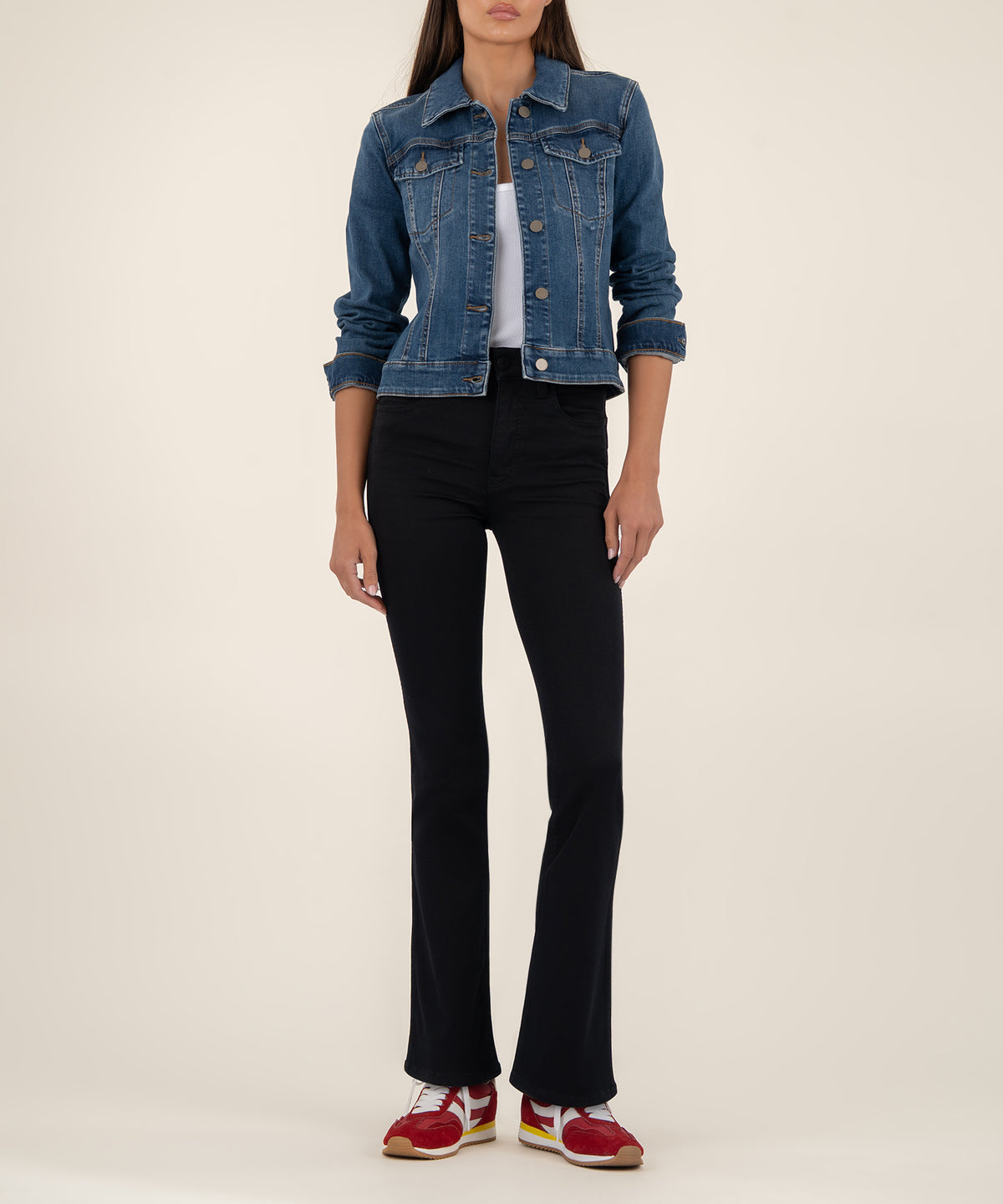 Cropped blue denim jacket with button front and chest pockets worn over white top and black pants.