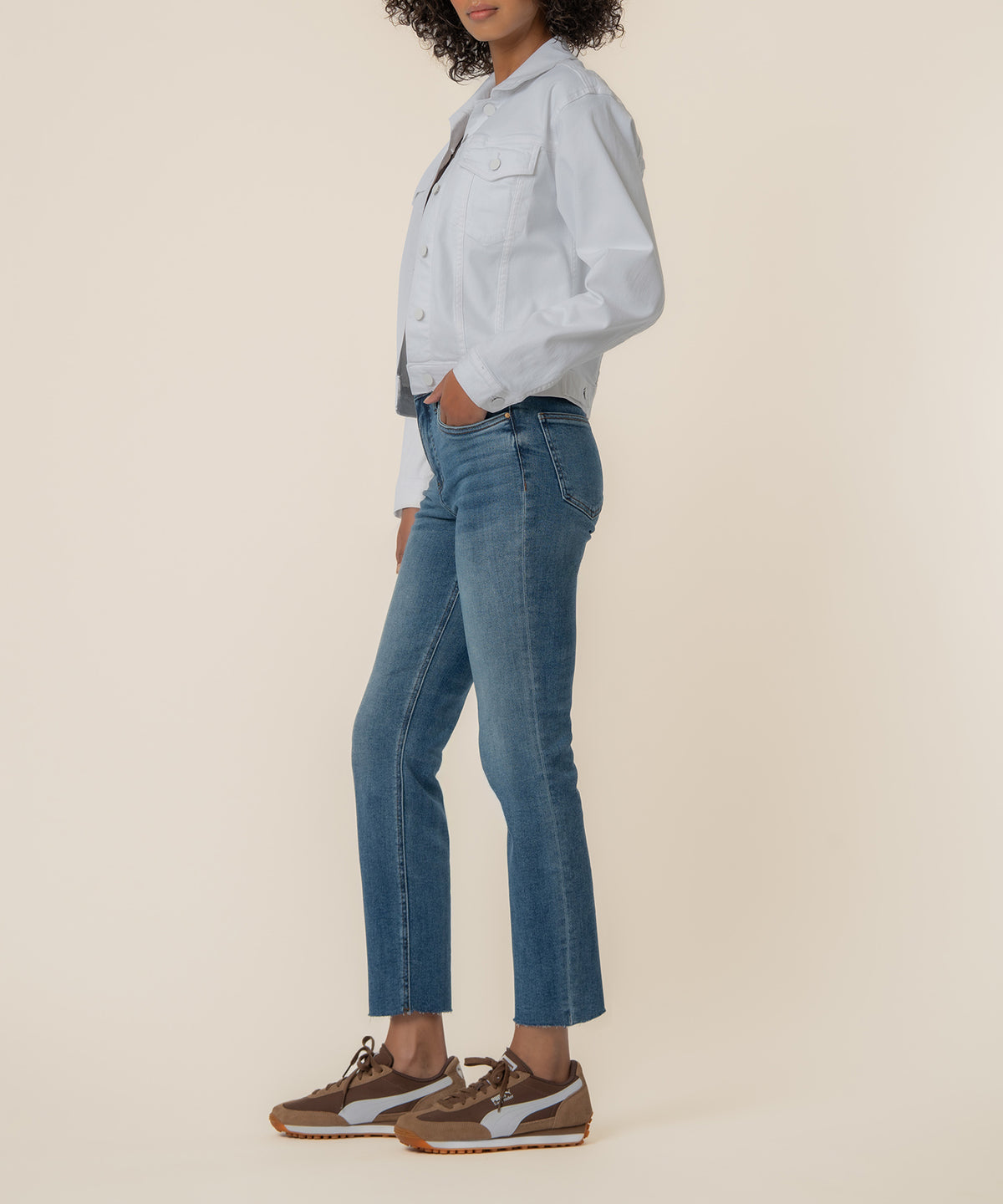 White button-up jacket with chest pockets worn with blue jeans and brown sneakers.