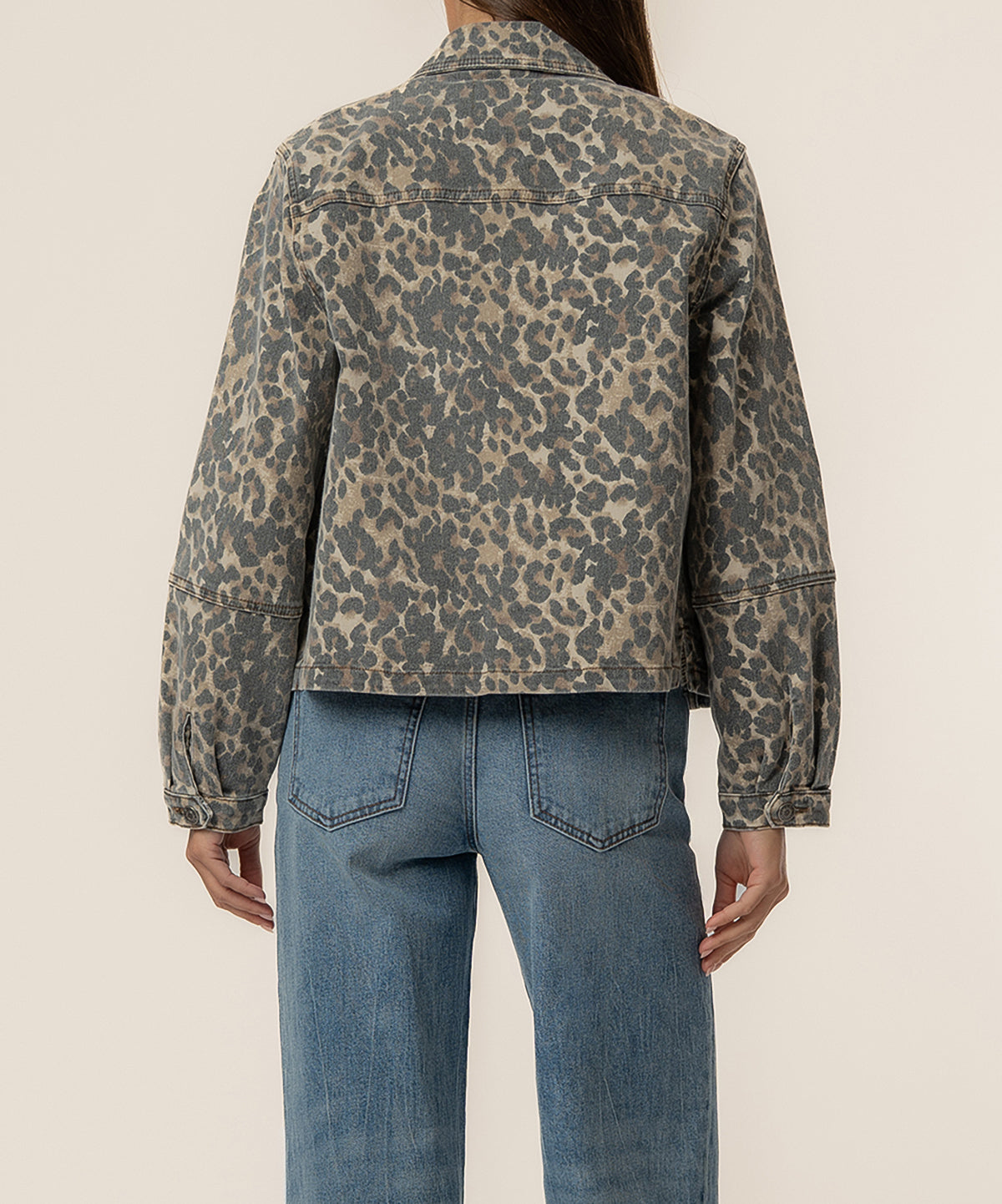 Tan and brown leopard print denim jacket worn on model shown from back, paired with blue jeans.