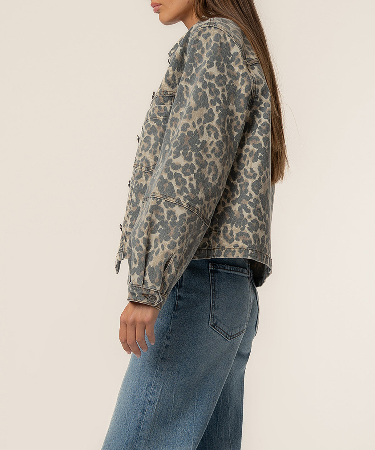Tan and brown leopard print denim jacket worn with blue jeans, shown from the side.
