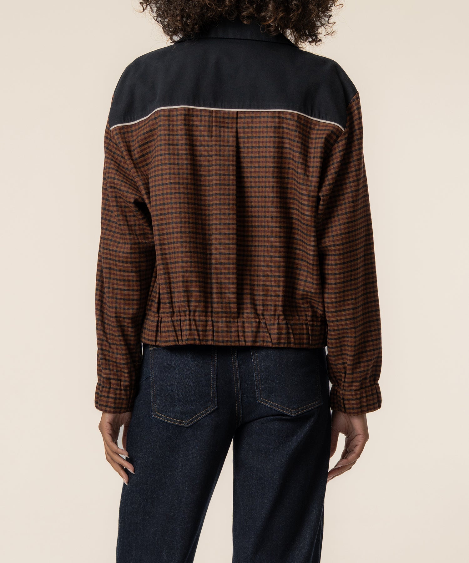 Black track jacket with brown gingham lower panels and white stripe trim, shown from back view.