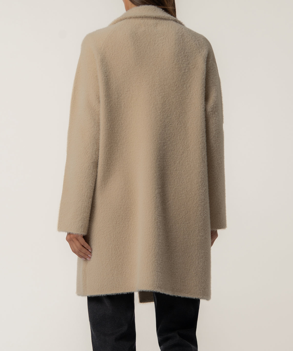 Oatmeal long sweater jacket with textured knit fabric, shown from back view on model wearing black pants.