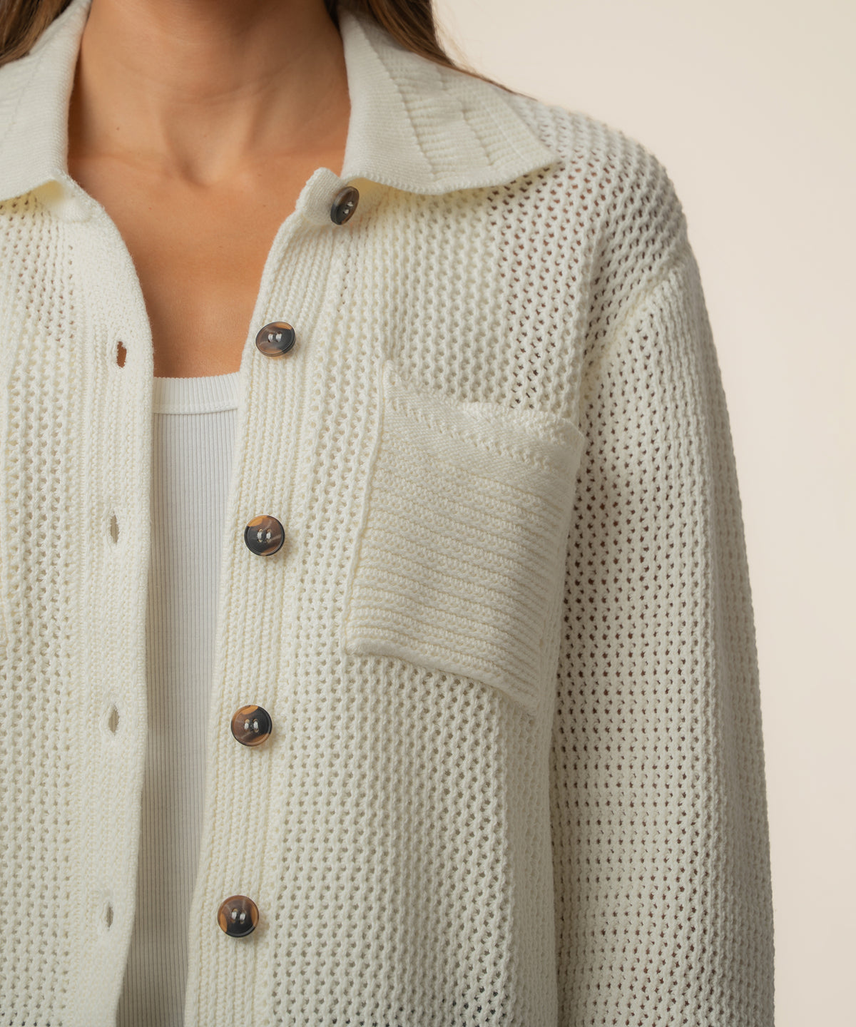 Cream knit cardigan jacket with tortoiseshell buttons, textured knit fabric, and patch pocket detail.