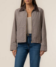 Chocolate brown and white gingham plaid jacket with collar and long sleeves on model wearing blue jeans.