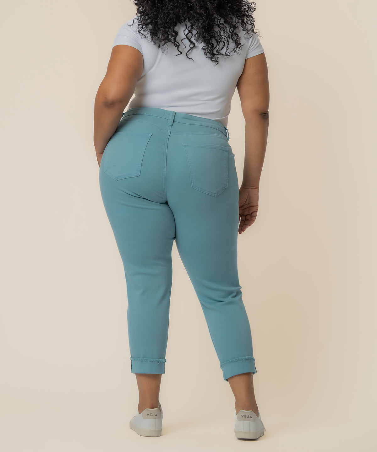 Cyan mid-rise crop straight leg jeans with cuffed ankles, shown from back view on model.