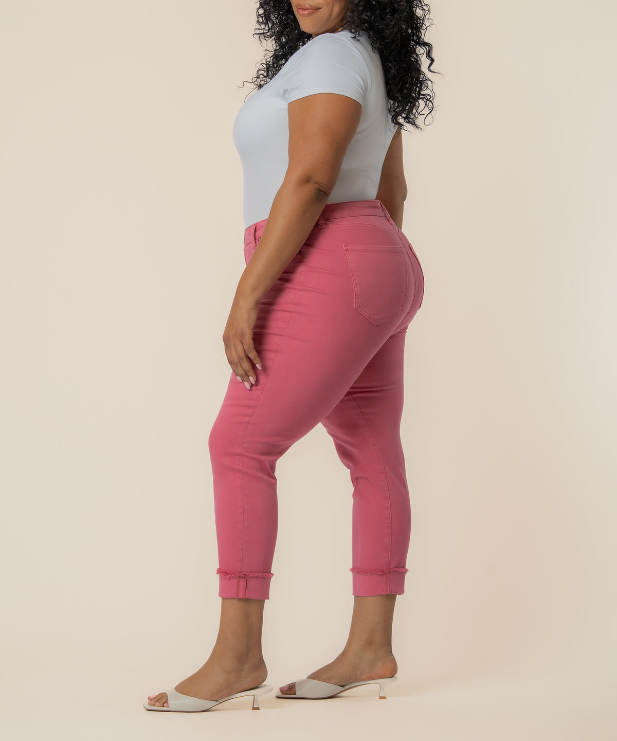 Woman wearing flamingo pink cropped straight-leg jeans with mid-rise waistband and rolled ankles, paired with white t-shirt.