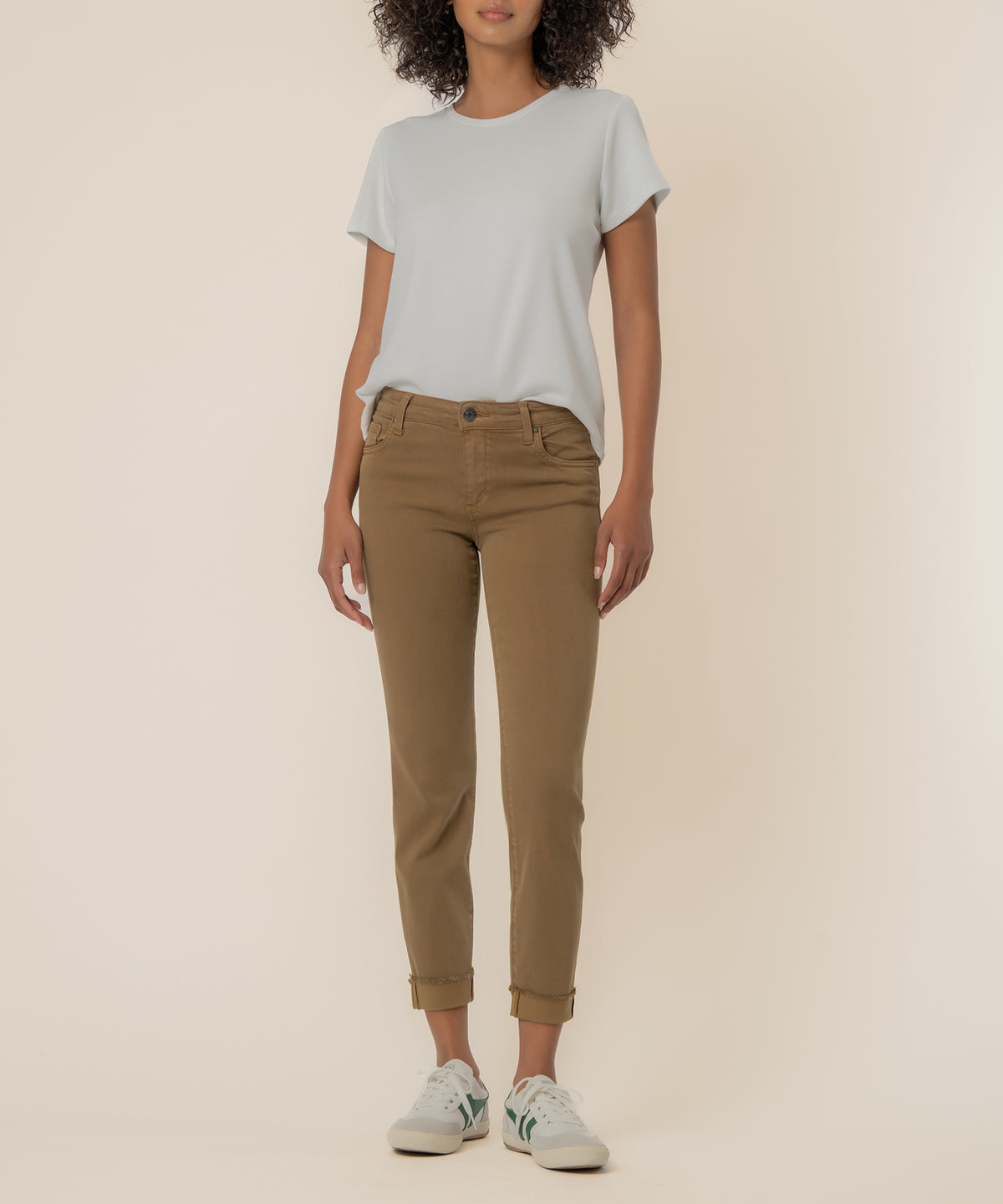 Woman wearing light gray t-shirt and brown cropped straight-leg jeans with rolled cuffs and white sneakers.