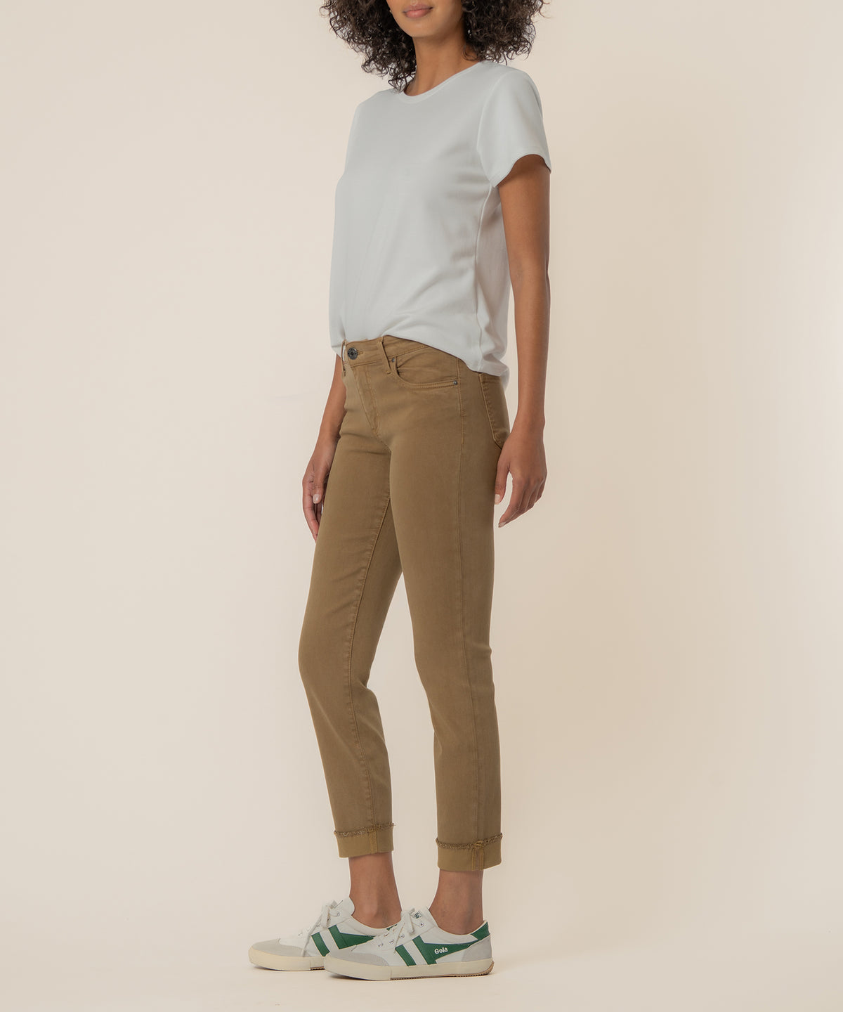 Woman wearing light gray t-shirt with tan mid-rise crop straight leg jeans and white sneakers with green stripes.