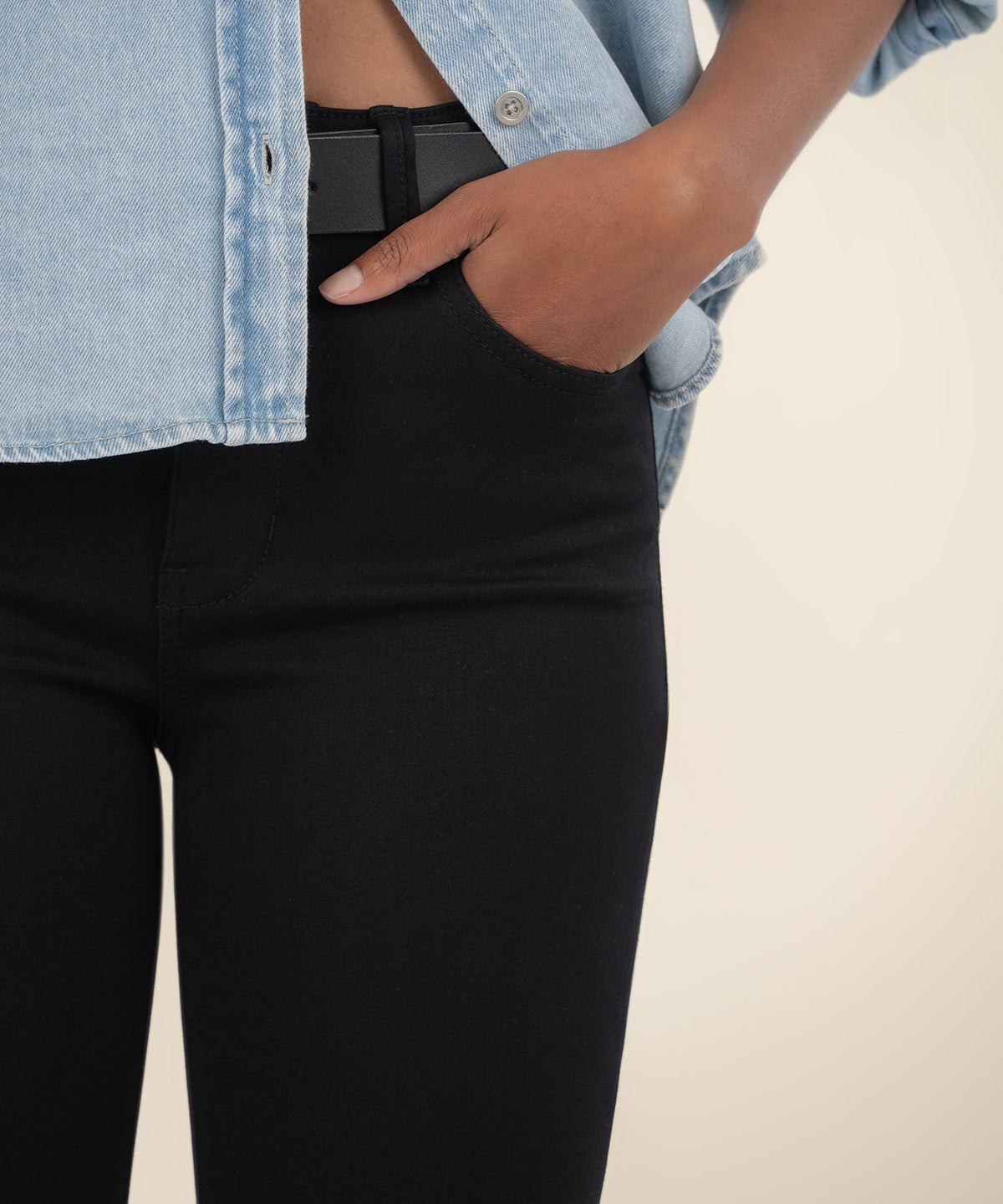 Black high-rise skinny jeans with button closure, styled with light blue denim shirt.