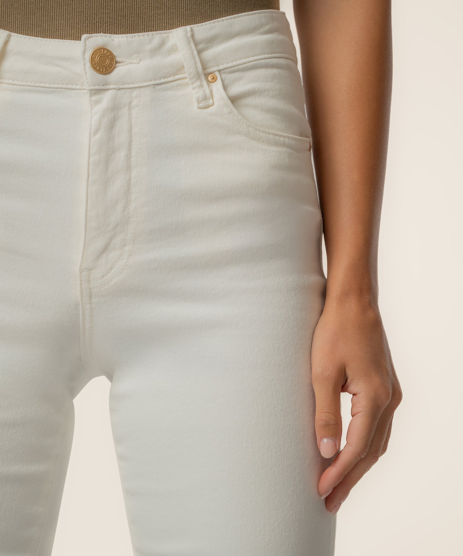 Cream-colored high-rise ankle flare jeans with gold button and zipper detail at waistband.