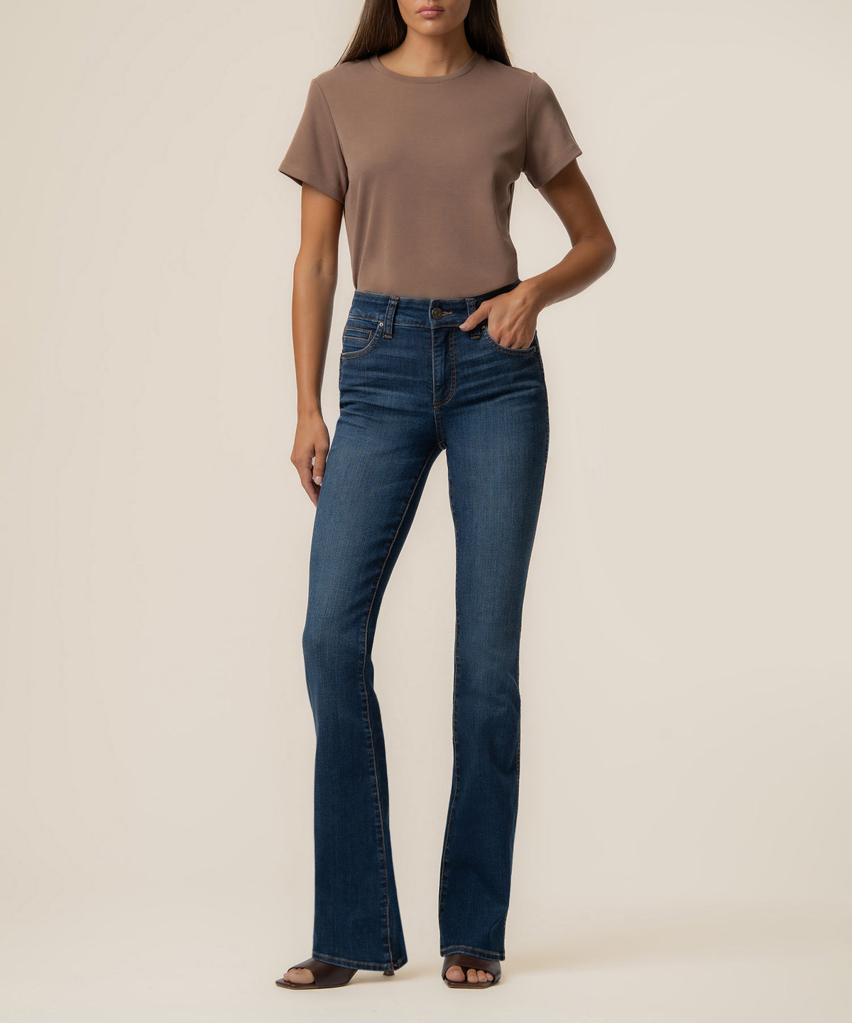 Woman wearing taupe short-sleeve t-shirt and dark blue high-rise bootcut jeans.