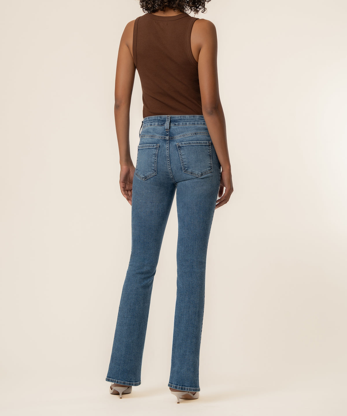 High rise bootcut jeans in medium blue denim with cracking wash and faded details shown from the back.