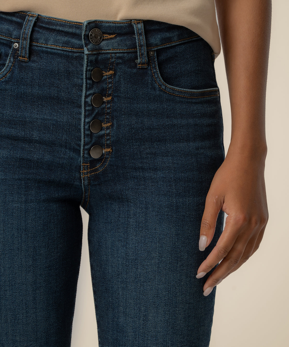 High-rise dark blue jeans with five-button fly and visible stitching detail at waistband.