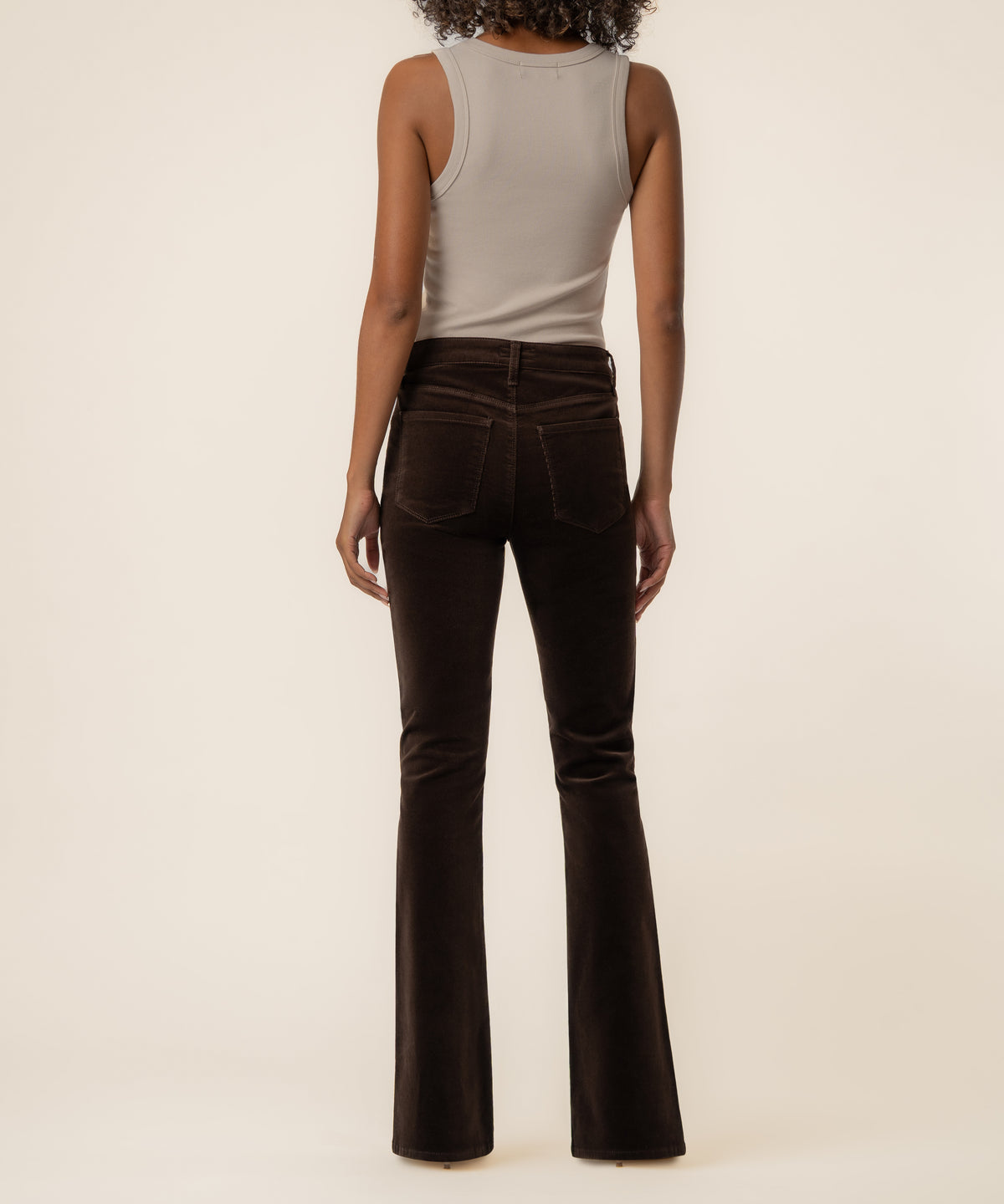 Brown corduroy high-rise flare pants with back pockets, shown on model from waist down.
