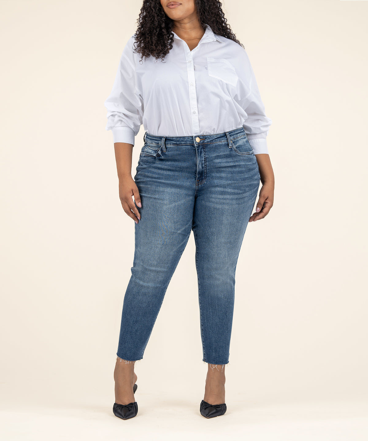 Woman wearing light-wash straight-leg ankle jeans with high rise and frayed hem, paired with white button-up shirt.