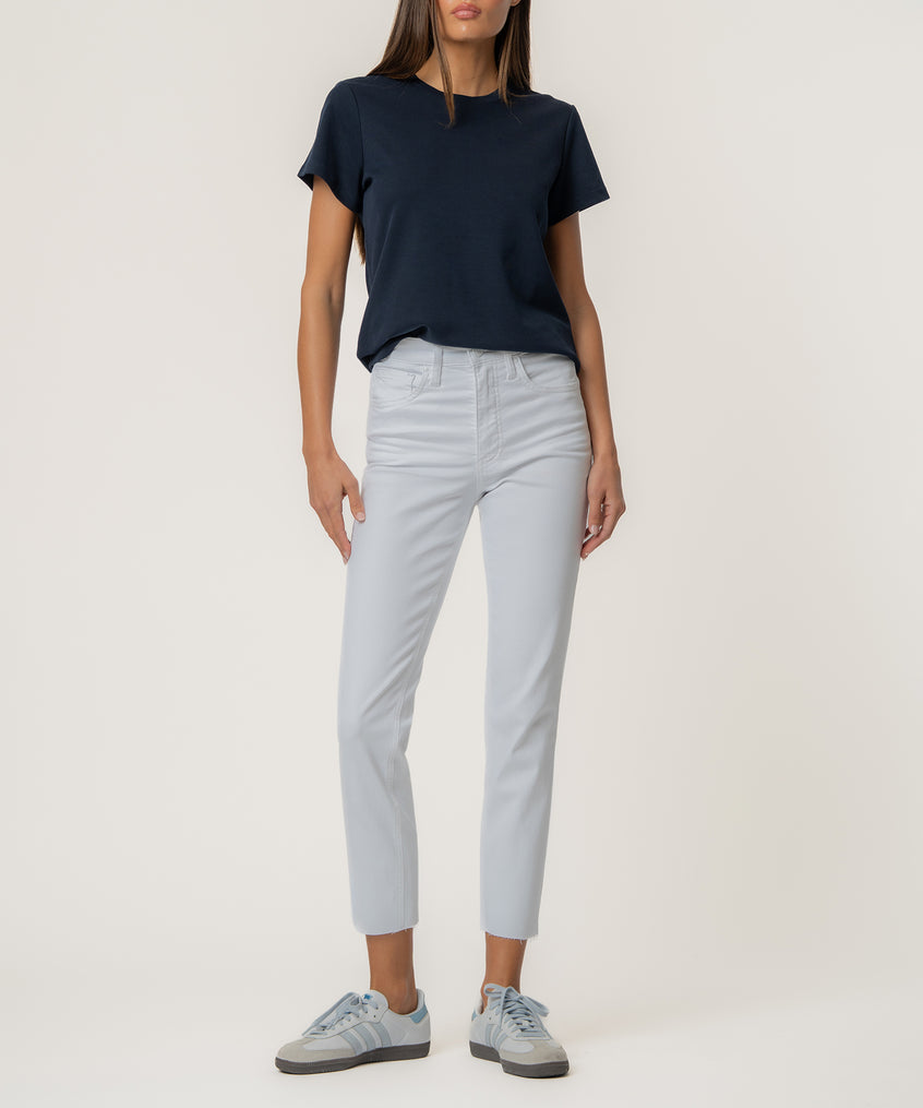 Woman wearing optic white high-rise mom jeans with a navy short-sleeve shirt and light blue sneakers.