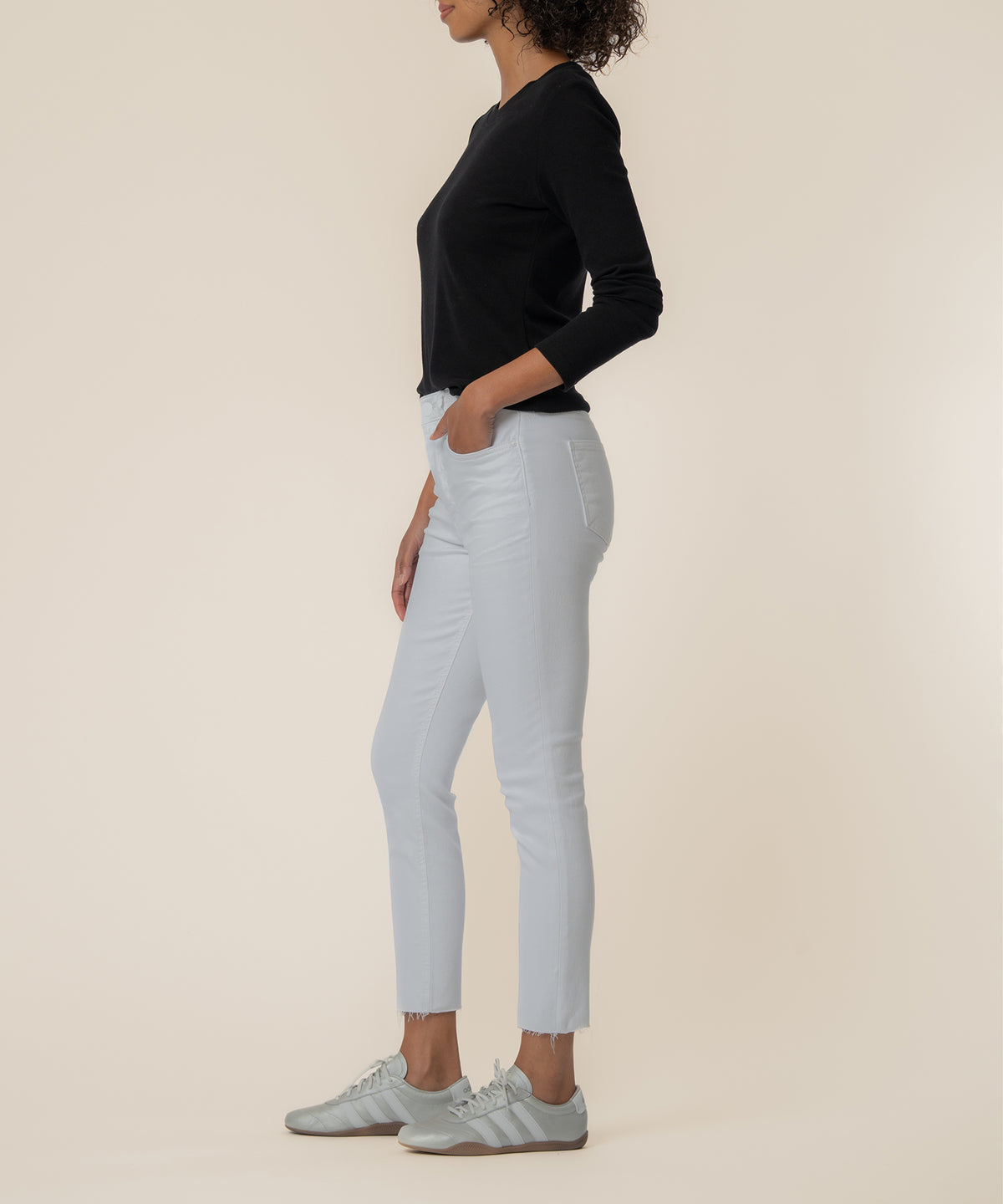 White high-rise mom jeans with cropped raw-hem ankle and front pockets, worn with black long-sleeve top.