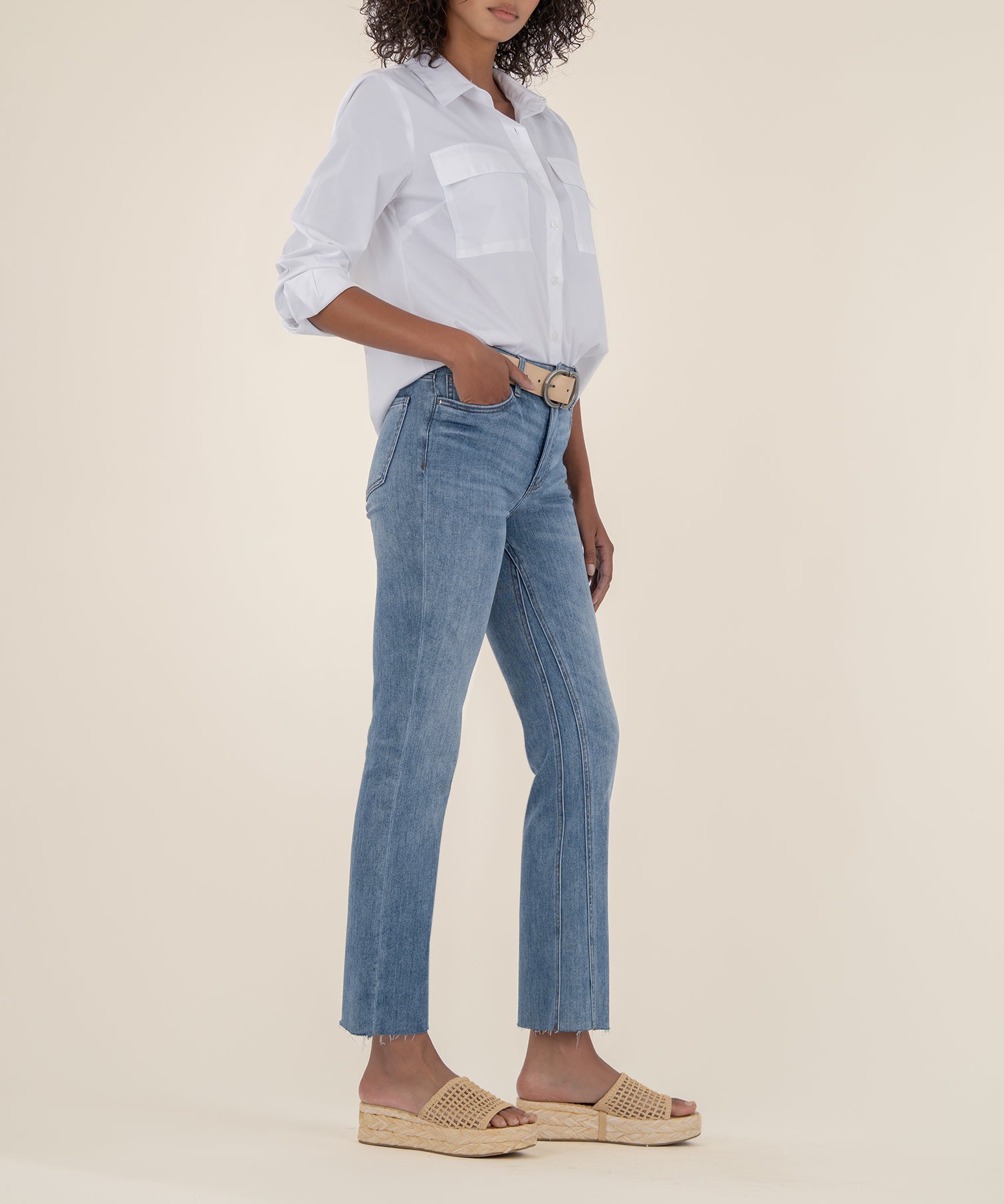 Light wash ankle flare jeans with high rise waistband and frayed hem, styled with white button-up shirt.