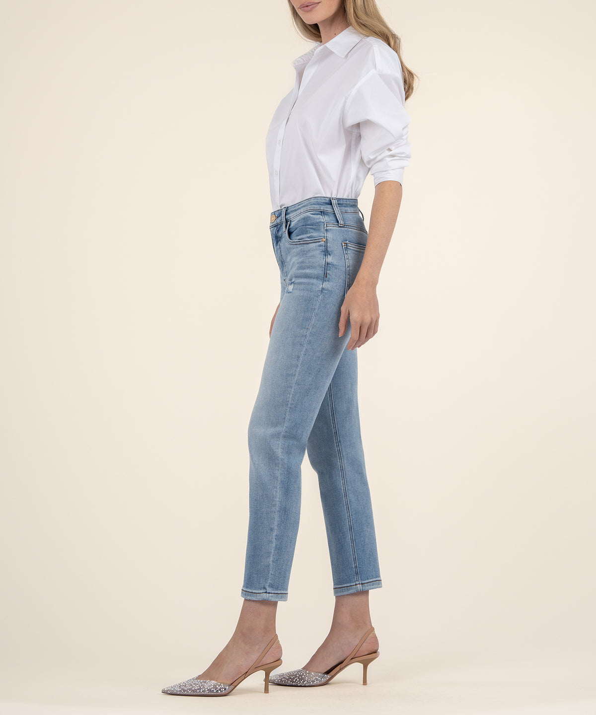 Woman wearing light blue high-rise mom jeans with white button-up shirt and pointed-toe heels.