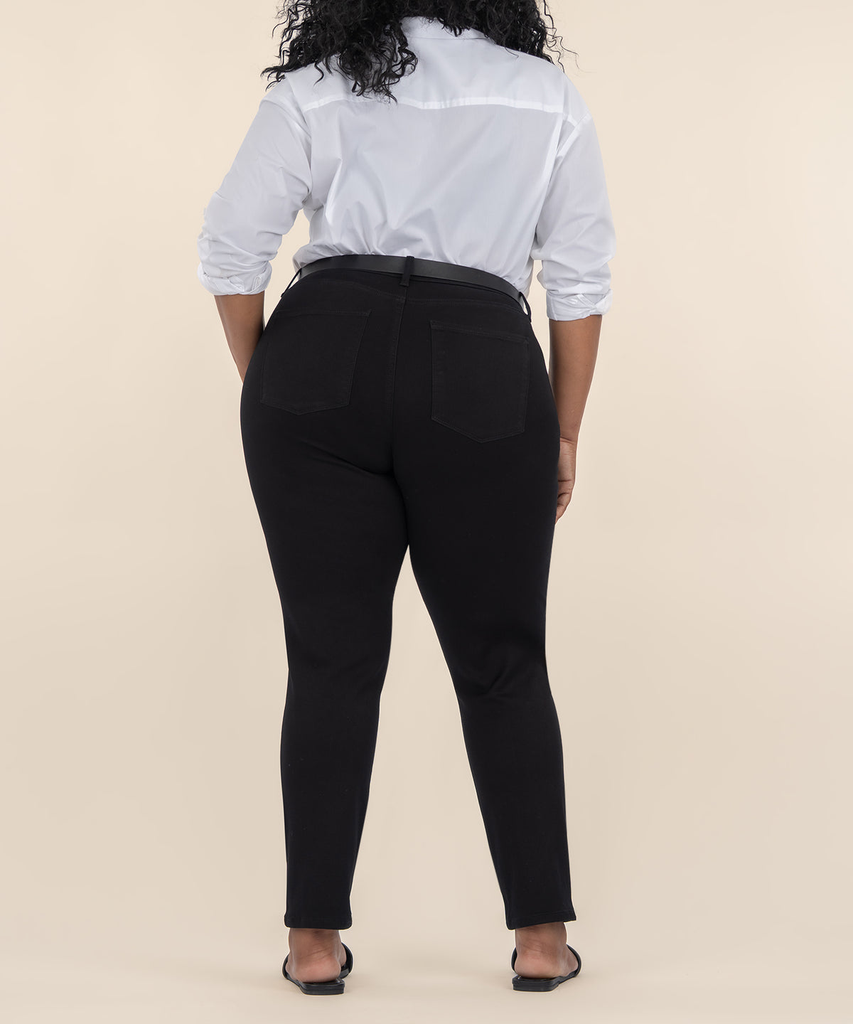 Black high-rise ankle straight jeans with five pockets, shown from the back on a model wearing a white shirt.