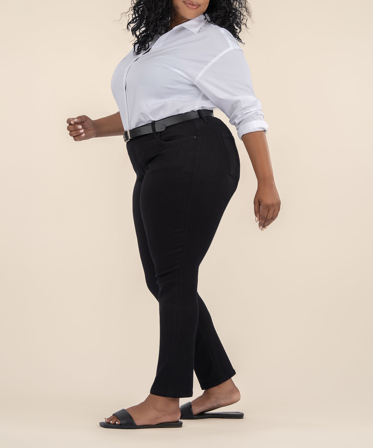Woman wearing black high-rise ankle straight pants with belt, paired with white button-up shirt and black slides.