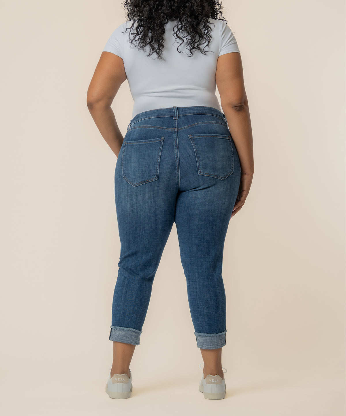Woman wearing light blue crop top and blue denim straight jeans with rolled cuffs and back pockets.