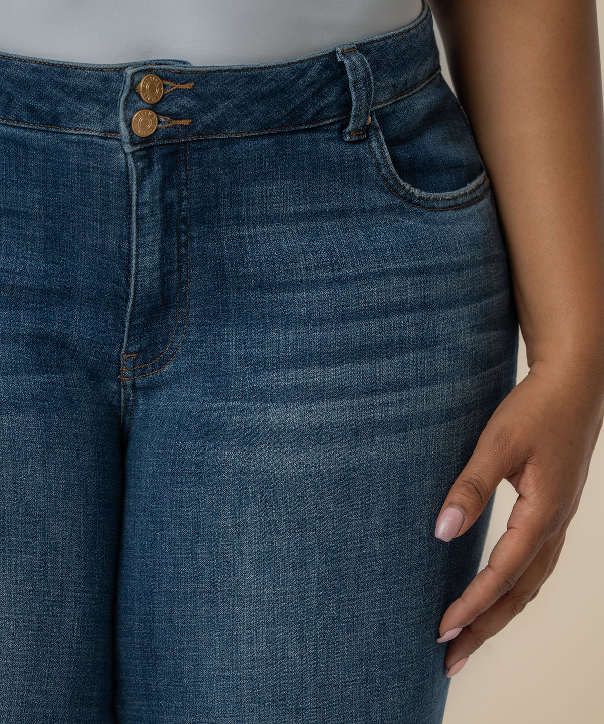 Mid-rise cropped straight jeans in dark blue denim with button closure and visible stitching detail.