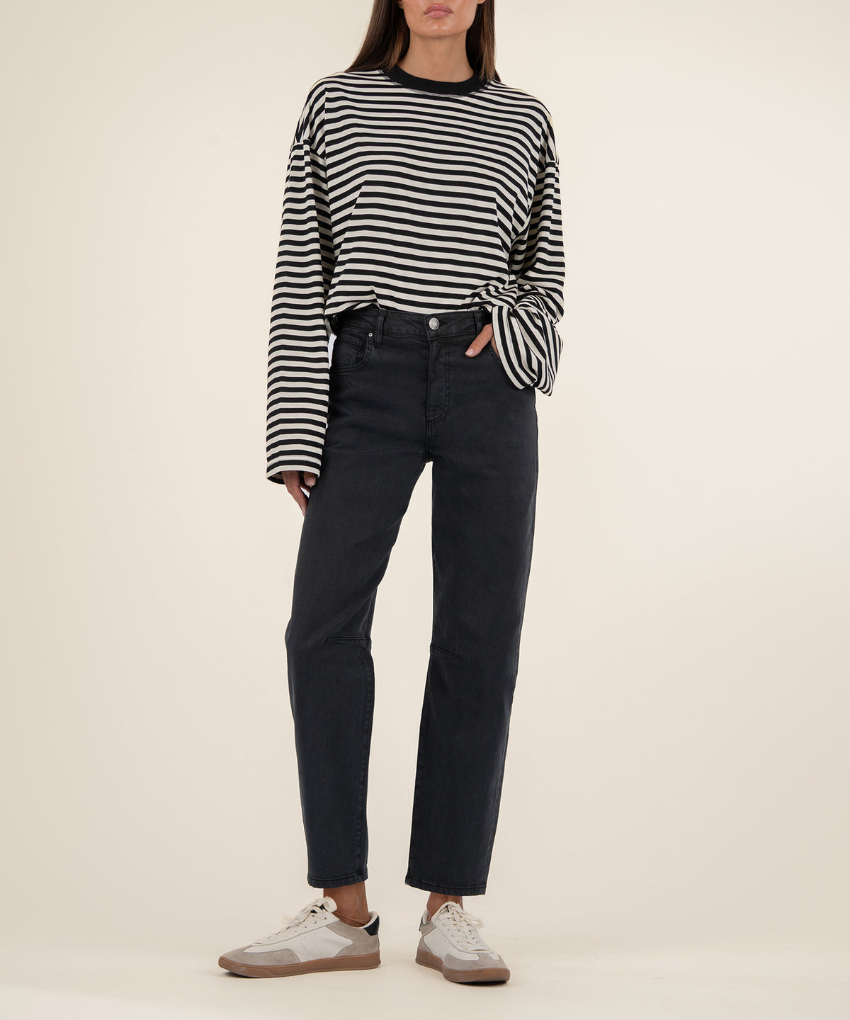 Woman wearing black high-rise straight-leg jeans with a black and white striped long-sleeve top tied at the waist.