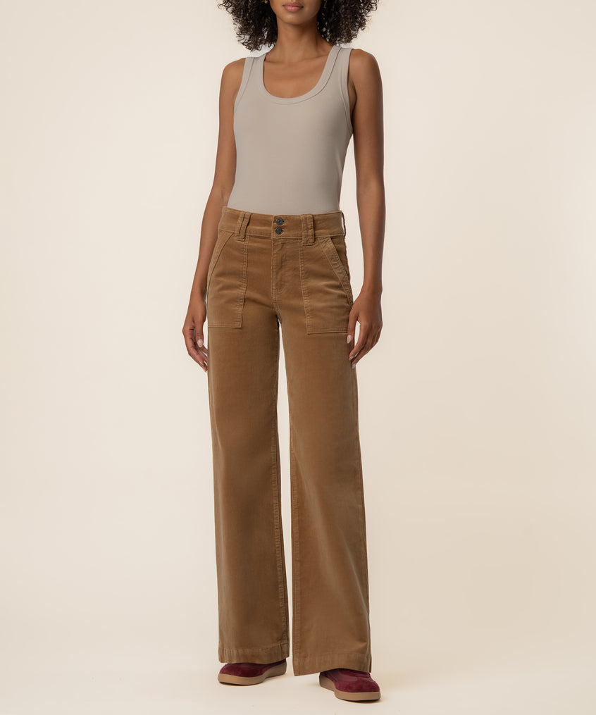 Camel corduroy high-rise wide-leg pants with cargo pockets and button fly on model wearing beige tank top.